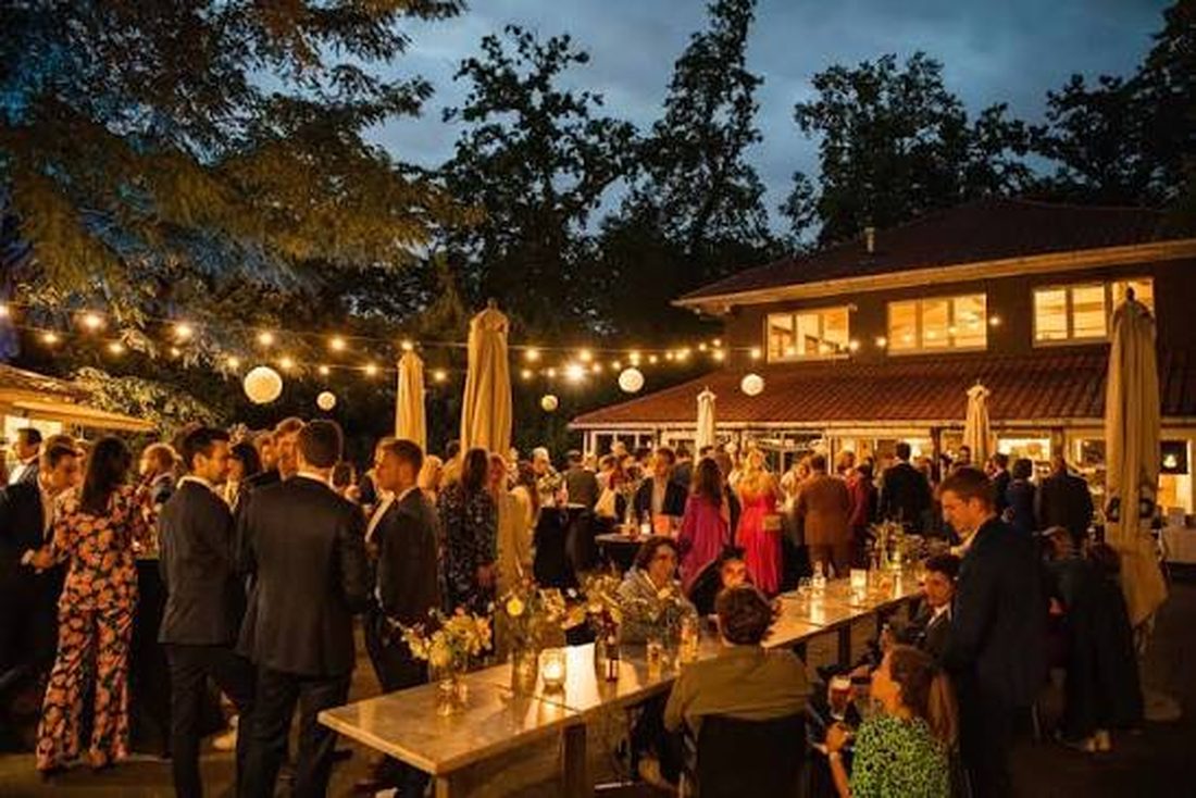 Gasten op het verlichte terras van 't Paviljoen bij avond